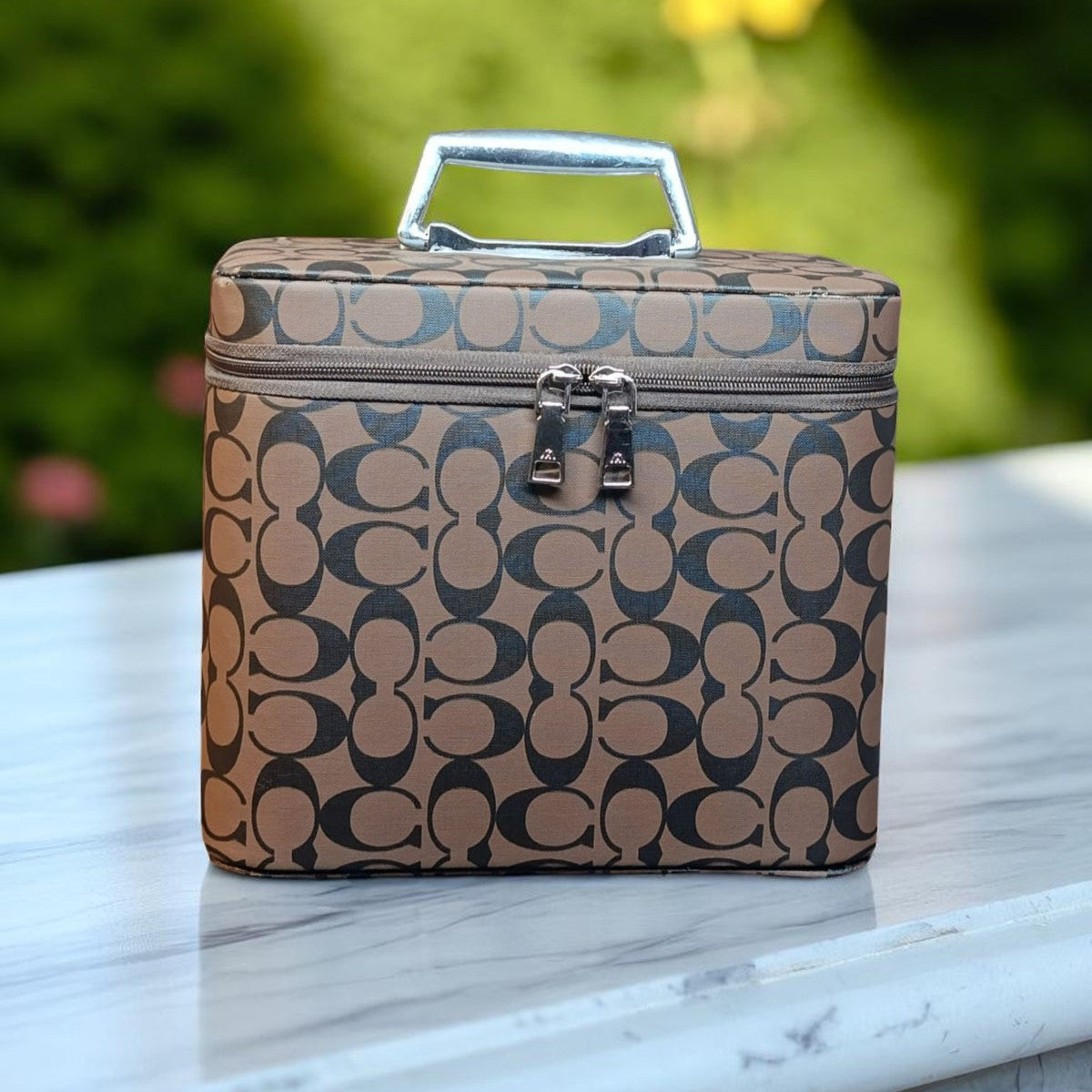 Coach patterned lunch bag on a marble surface with a blurred green outdoor background